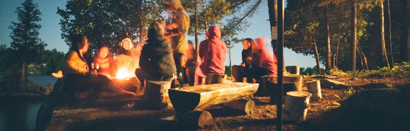 A group gathered around a campfire under a deep blue evening sky